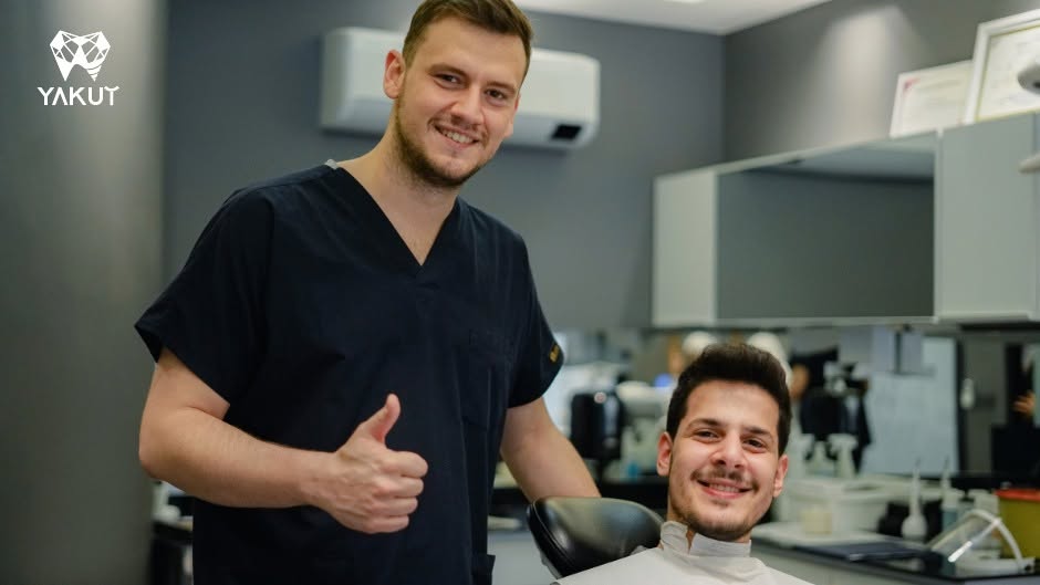 Yakut kliniğinde bir hekim ve diş ünitesinde oturan kişi